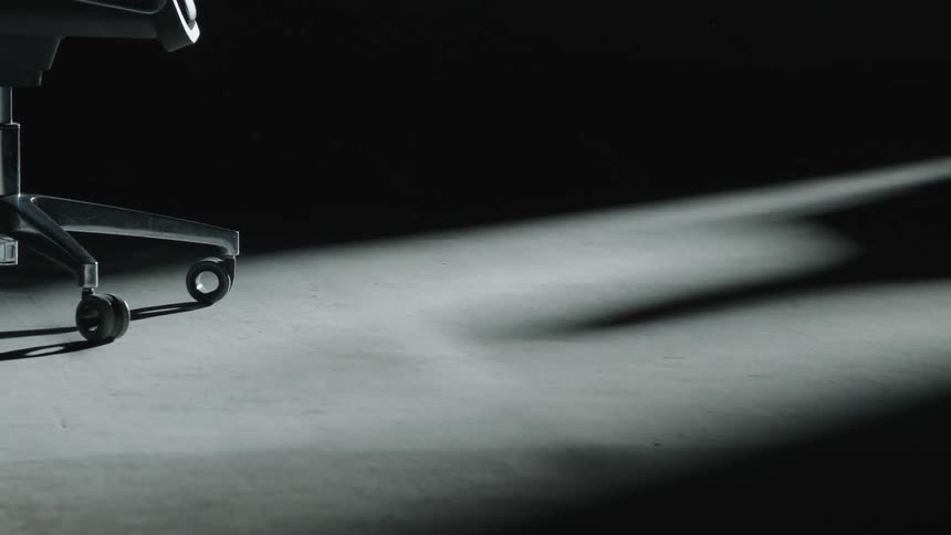 In a darkened room the shadow of a person can be seen as they walk away