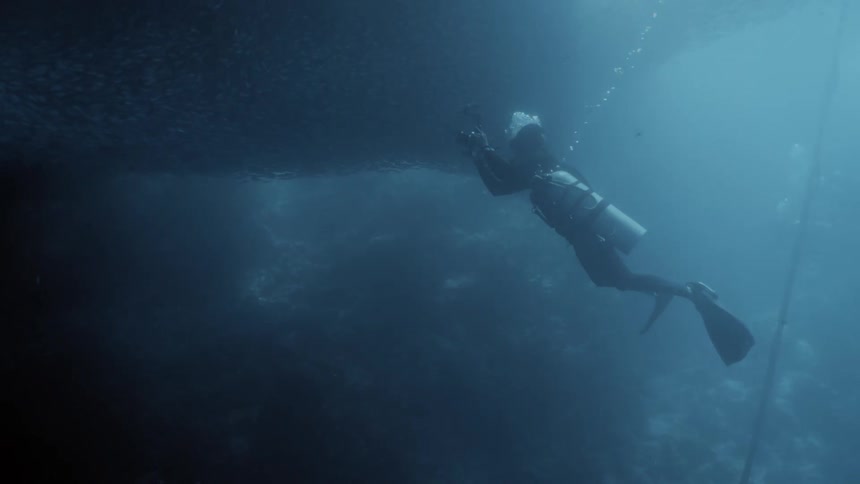 A diver photographing a ship at the bottom of the ocean