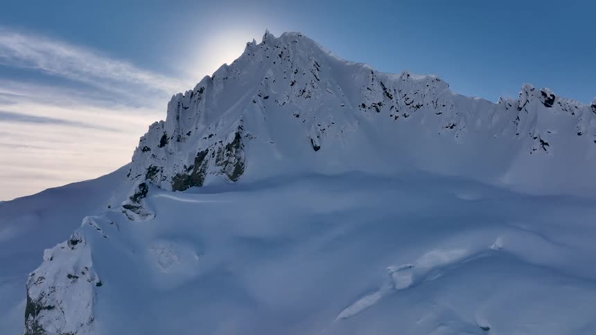 Aerial view of the peaks of a snowcovered mountain with the sun reflecting