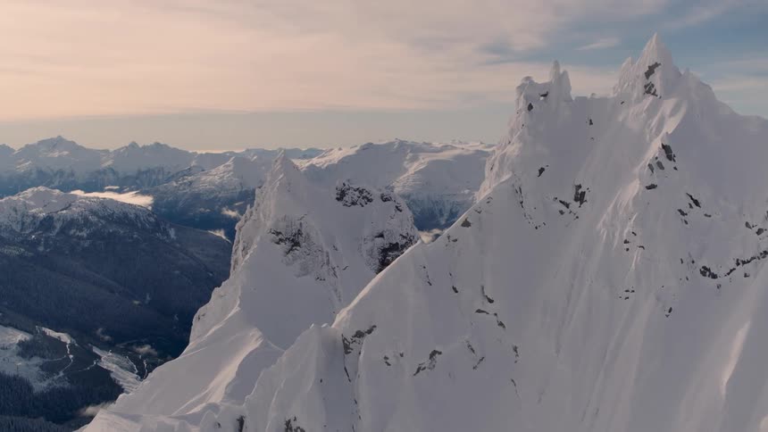 An aerial view of a snow covered mountain landscape on a cloudy day