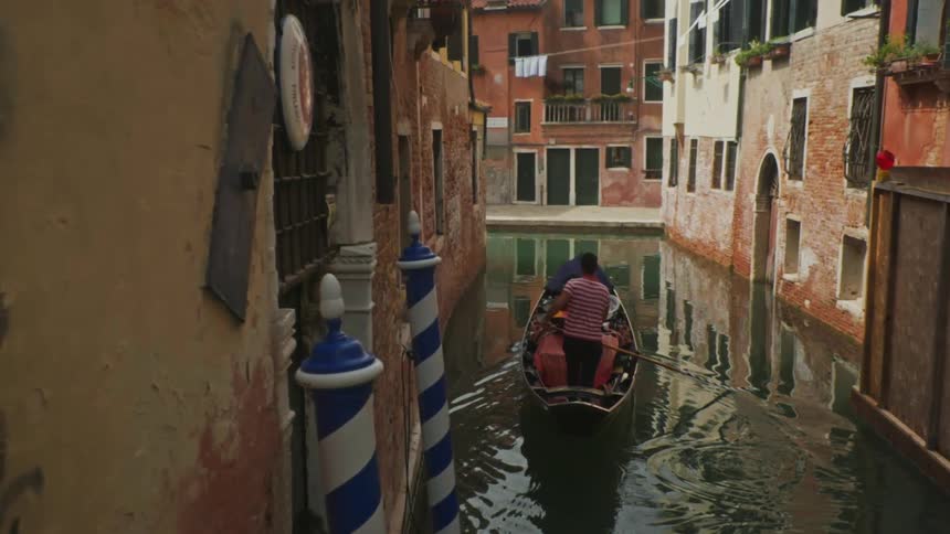 A man is rowing a boat in the small canal