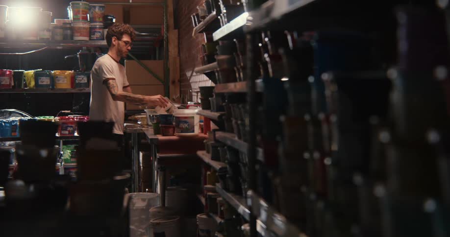 A man with paint cans in a shed