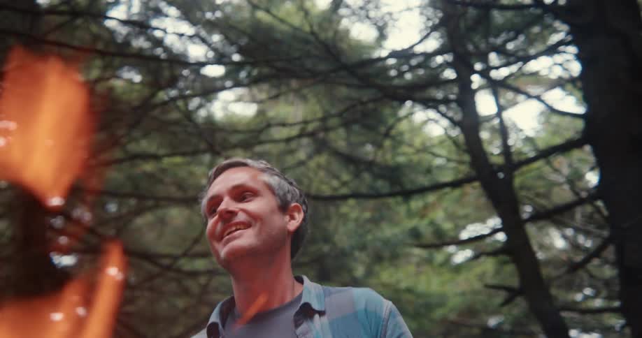 A man smiling and looking to the side while there is a flame of fire in front of him