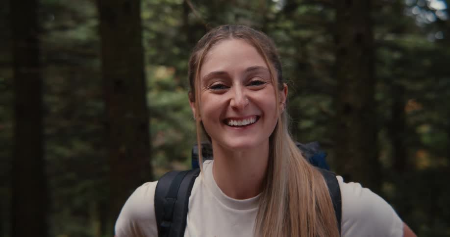 Young woman with a backpack smiling in a forest