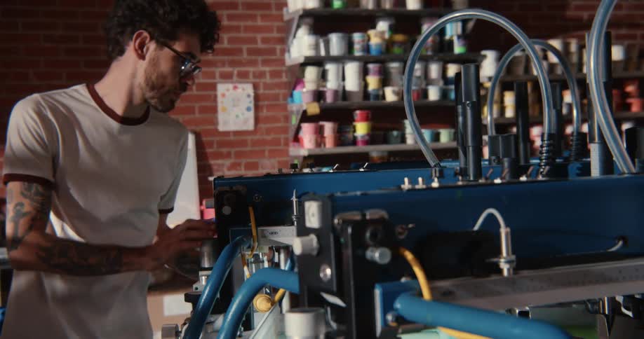 Young man adjusting printing machinery in the workshop