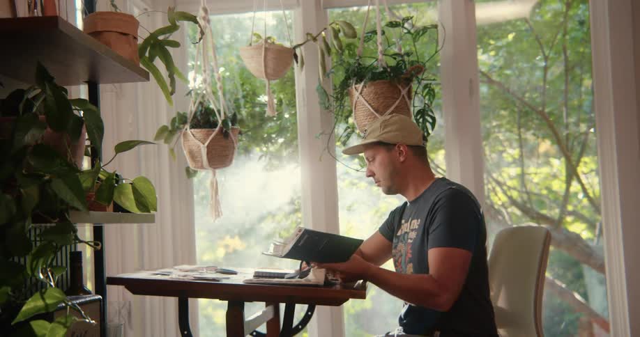 Man reads a notebook nex to the garden