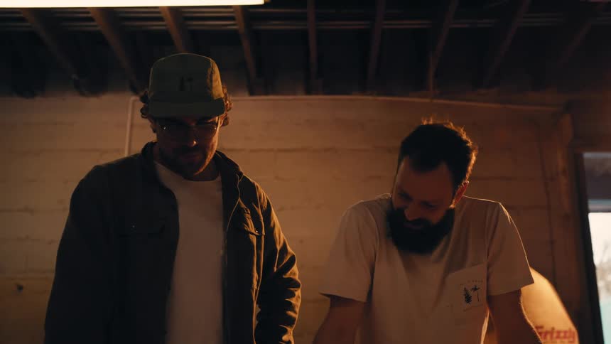 Two men standing in a room looking at the floor