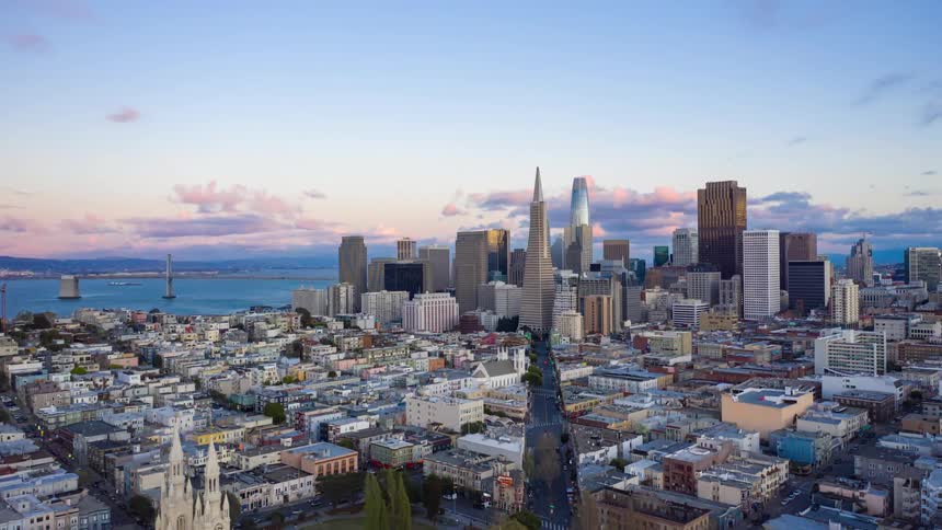 A time lapse of San Francisco with huge buildings and a sea behind it