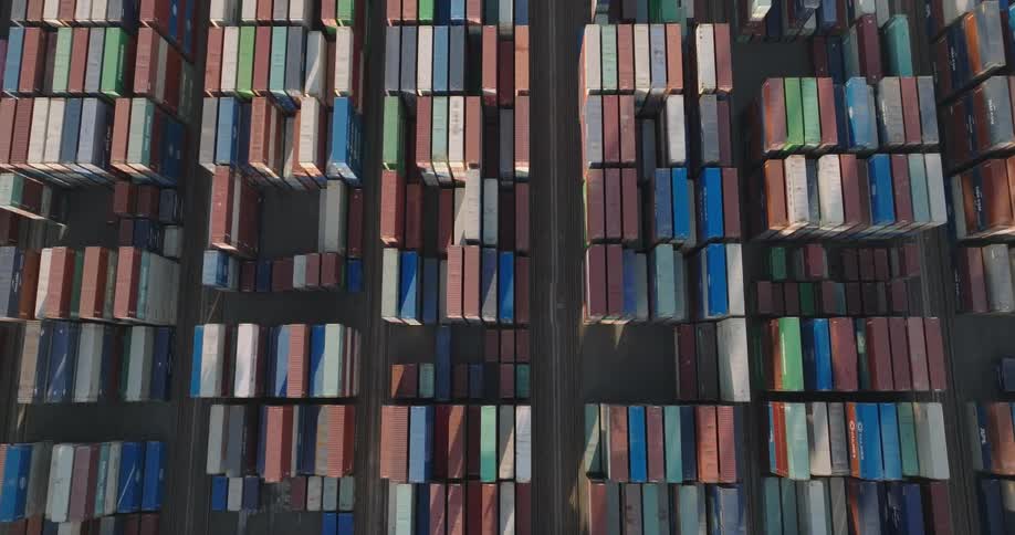 Loading cranes tower over stacked layers of shipping containers