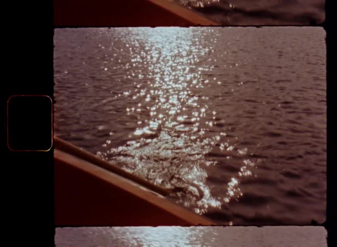Old wooden paddle propelling a canoe or rowing boat through the water of a lake as the sun reflects on the rippling surface of the body of water with nostalgic Super 8mm retro vibes on film