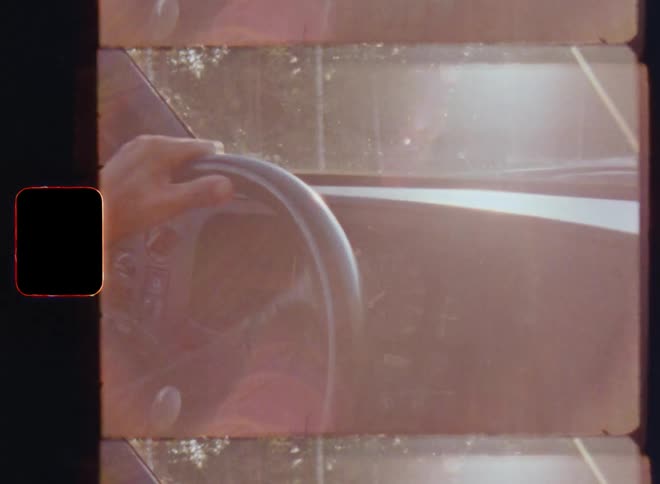A person starts the ignition of an automobile motor or engine by turning the car key and leaves driving onto a road or street as the sun shines through the windshield illuminating the dashboard by a flare or glare of sunlight filmed on vintage Super 8