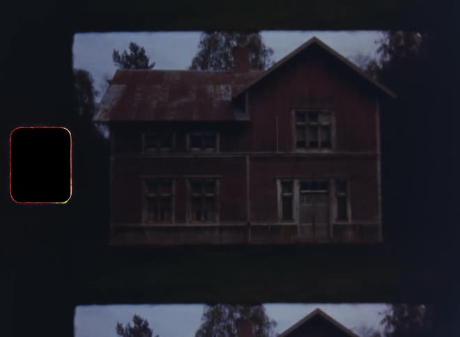 An old abandoned twostory red house is nestled in the trees