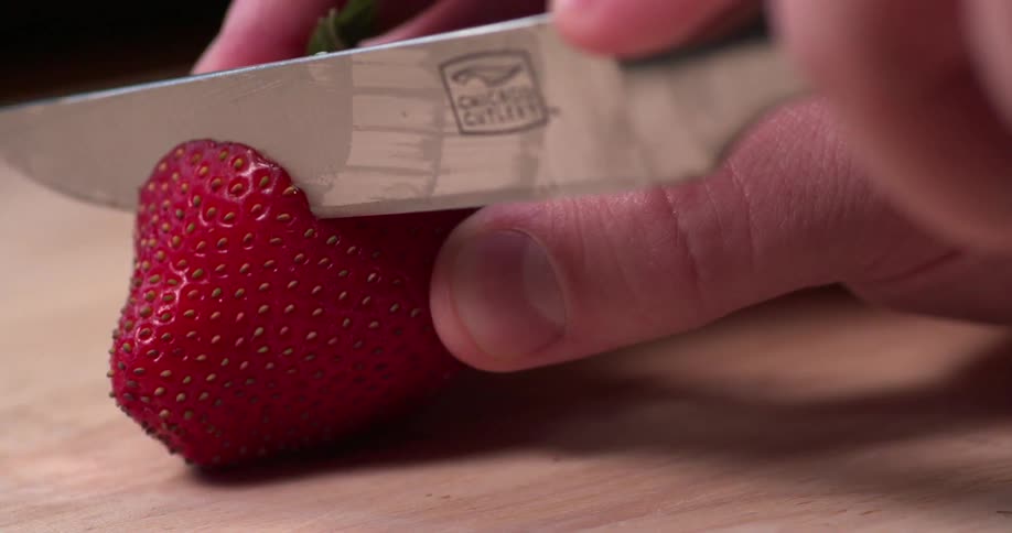 A knife cuts a strawberry