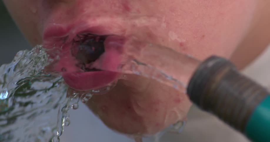 A man is drinking water from a hose
