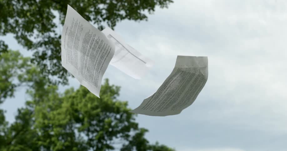 Pages of paper with print on them fall in the air