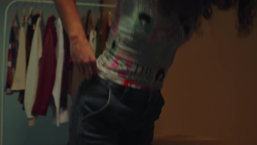 Teen adjusts her top and jean while standing in a room