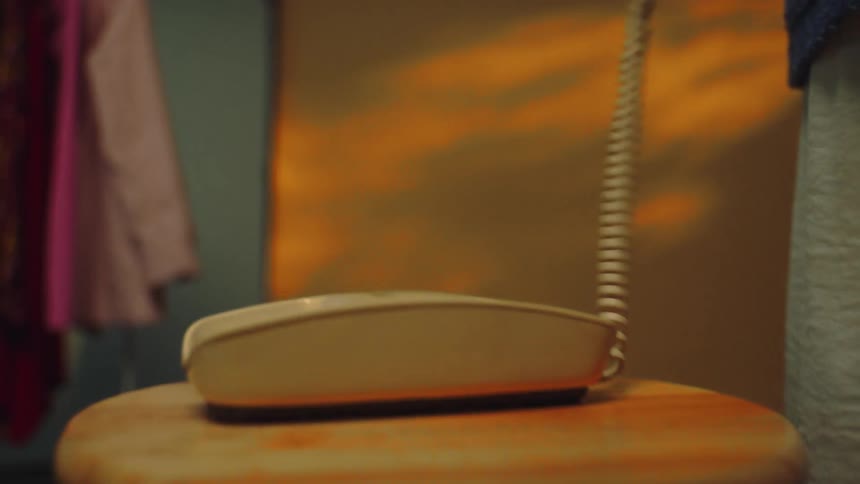 Lady answered a call on a landline placed on a stool in a room