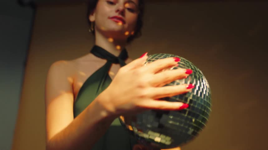 Smiling young girl in a dress holding a disco ball and spinning it