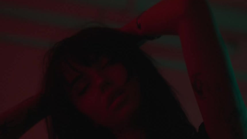Woman with tattoos and bangs haircut dances in red lighting