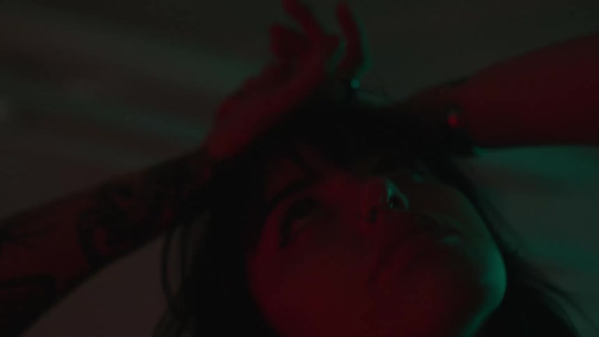 Woman with hands on her head dancing with lights reflecting on her face