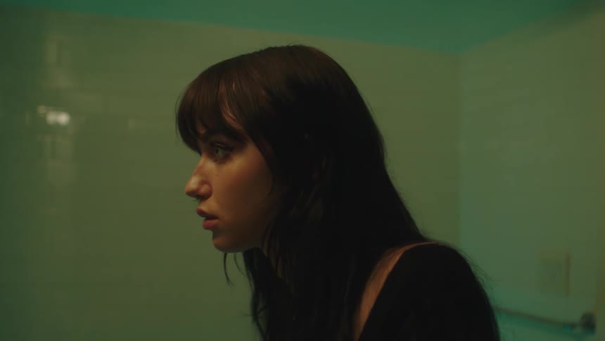 Portrait of a woman in the bathroom applying lip gloss to her lips