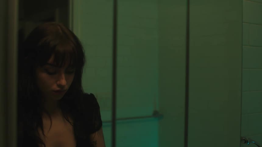 Young woman enters a dimly lit bathroom to fix her makeup