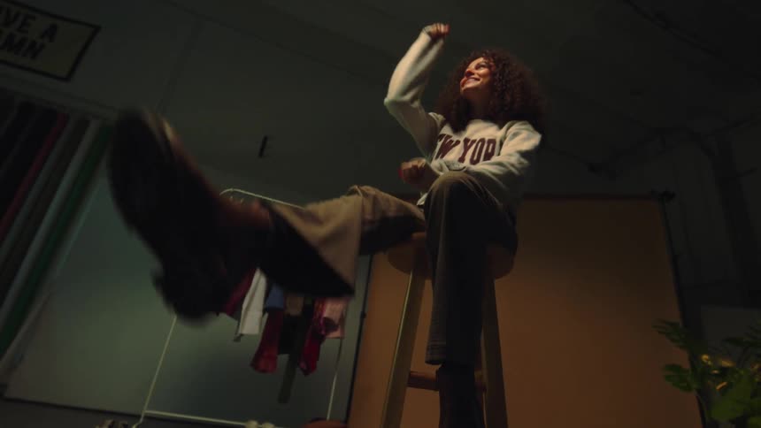 A woman is dancing as she sits on the stool