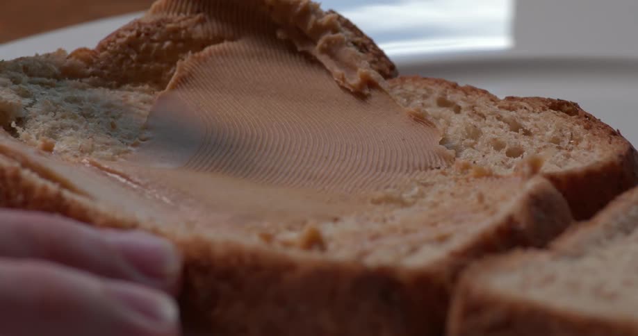 Peanut butter is being put on bread