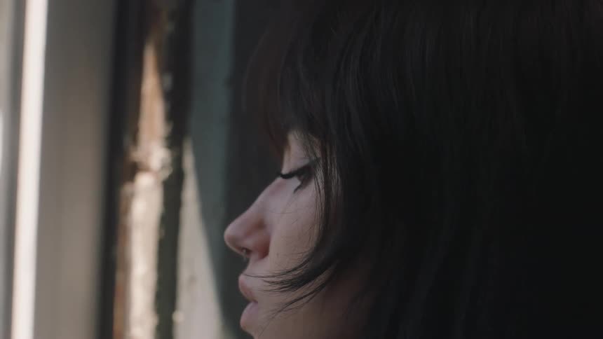 A female sitting by a window looking sad