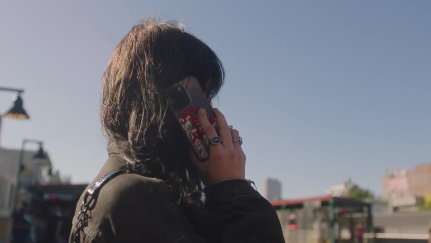 A lady standing in the middle of the street trying to make a call