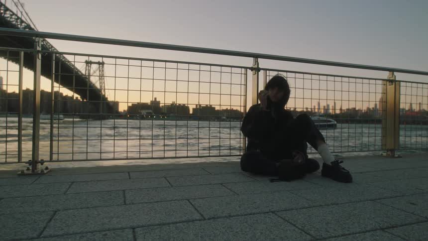 Young woman sits near the river looking at the city