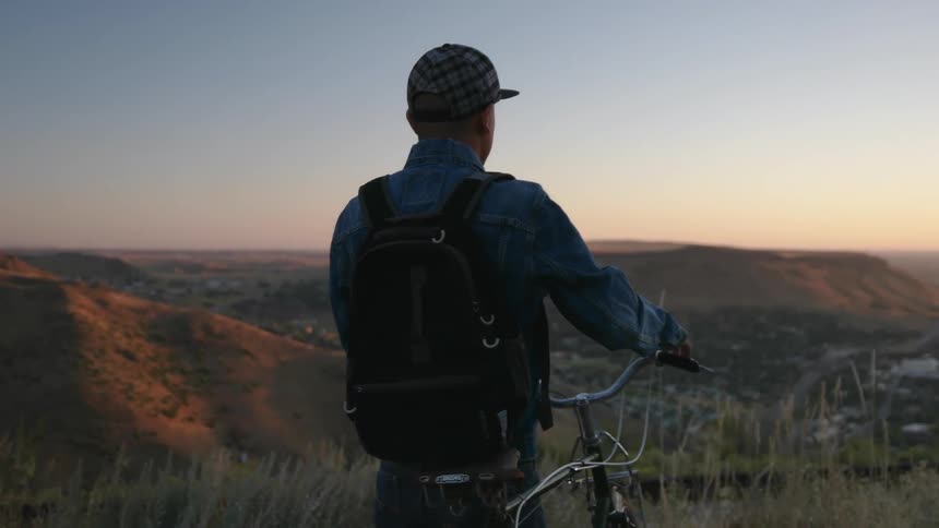 A man pushes his bike near the top of a mountain roadside