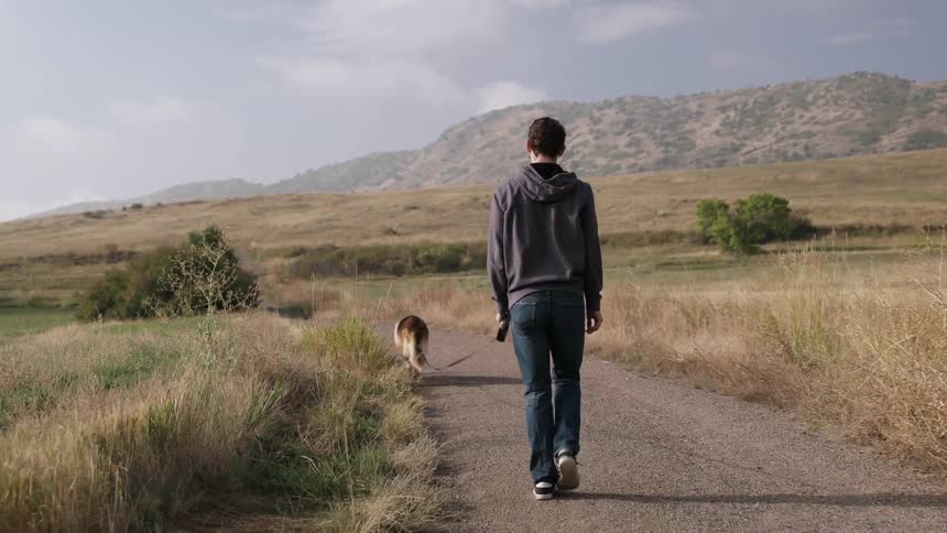 A man is walking his dog down a trail