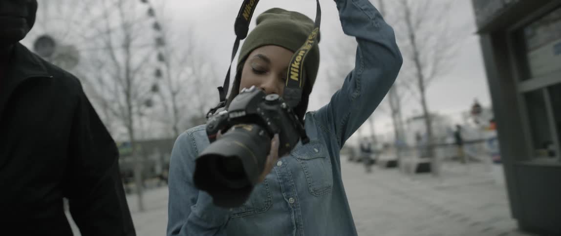 A woman puts a camera strap around her neck
