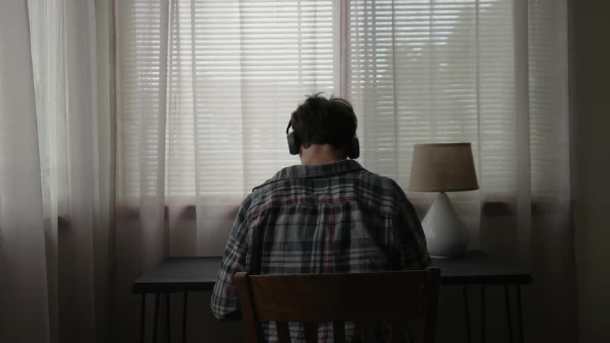 A man sits at the table wearing headphones