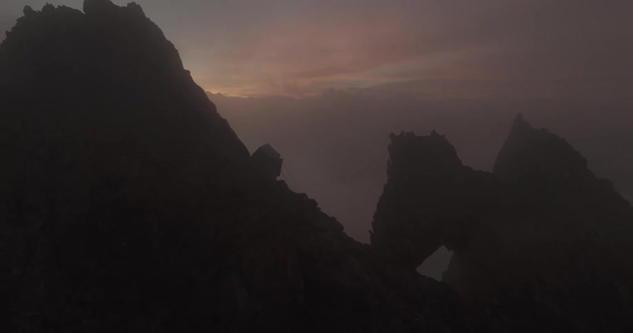 A cabin high on a rocky mountain at dusk