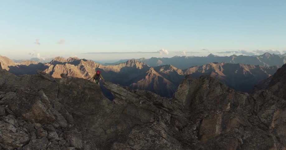 Skyline of a person climbing a rock mountain at sunset