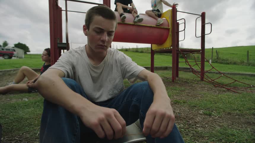 Young man sitting in an amusement park corridor with a disheartened facial expression