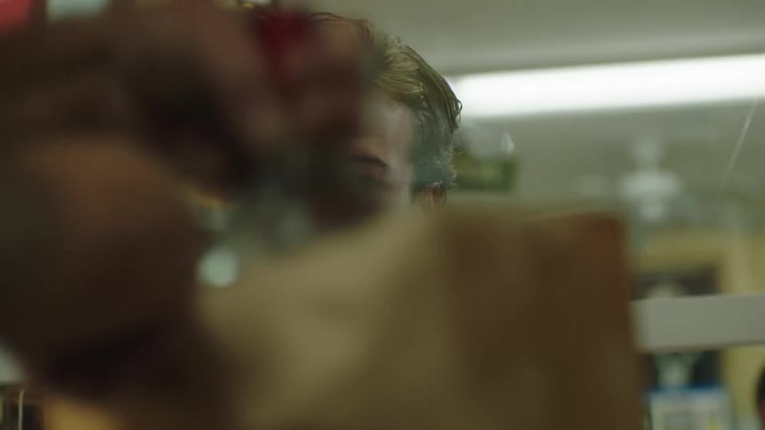 Man waits while items are bagged in a liquor store