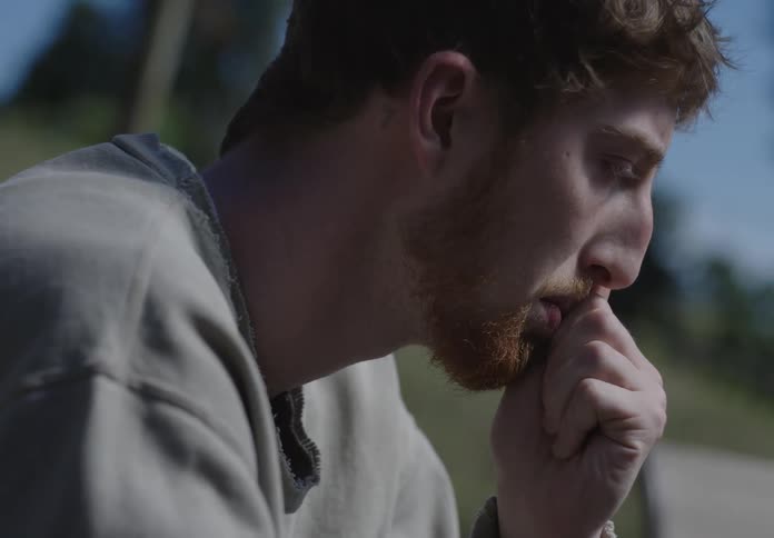 A man sits with his fist covering his mouth deep in thought