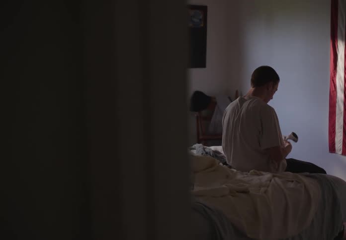 A boy in his room putting on a pair of socks