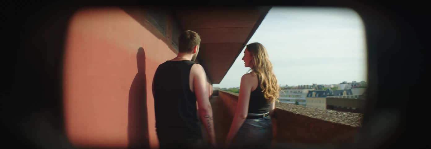Young man and young woman walking on a corridor in a balcony having a tense conversation during day time