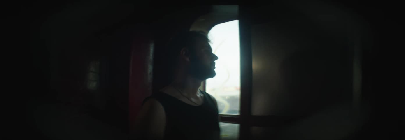 A sad man watching the landscape through the window