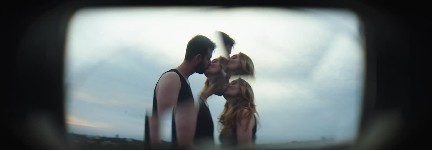 A man and woman pose for the camera and then turn and kiss each other