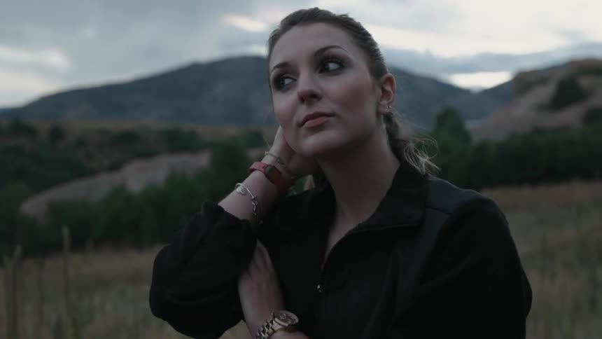 A woman is walking along a field on a cloudy day