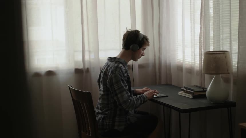 A man is sitting at a desk using a tablet