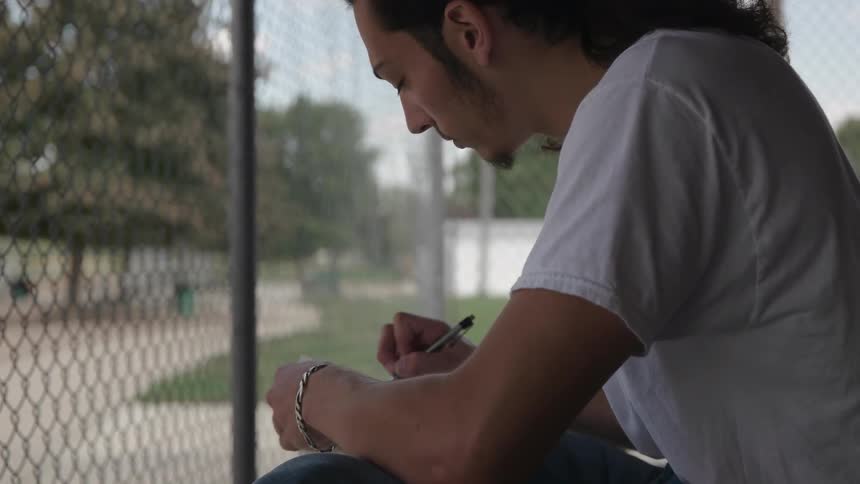 A man is writing in his notebook outside