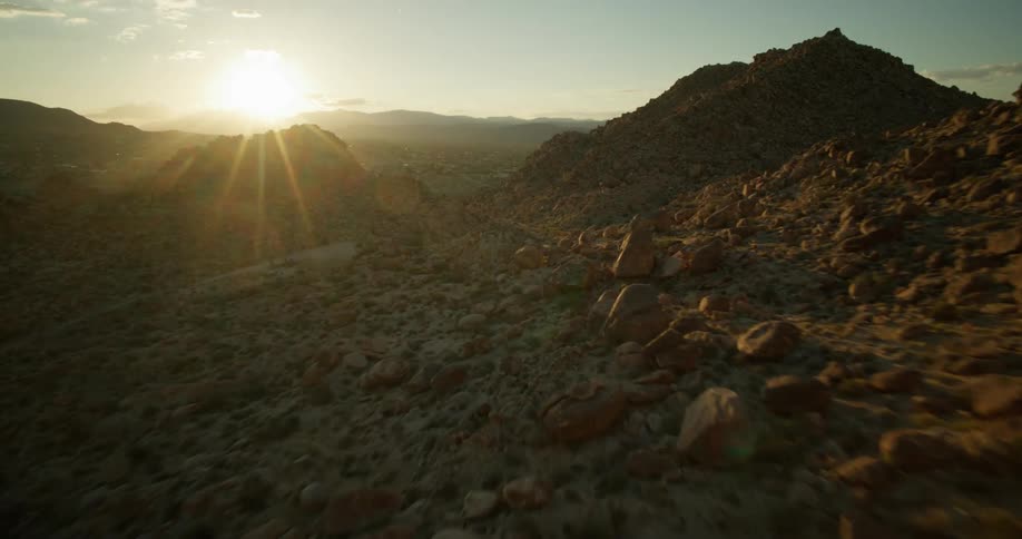 Sun shines onto rough mountainous terrain strewn with rocks