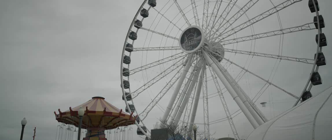 A large ferris wheel sits in a cloudy sky