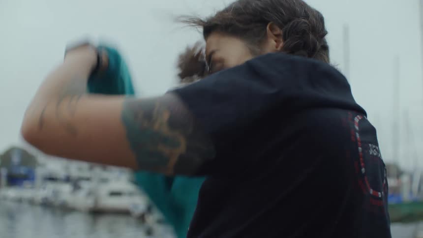 A woman taking off her coat in a marina